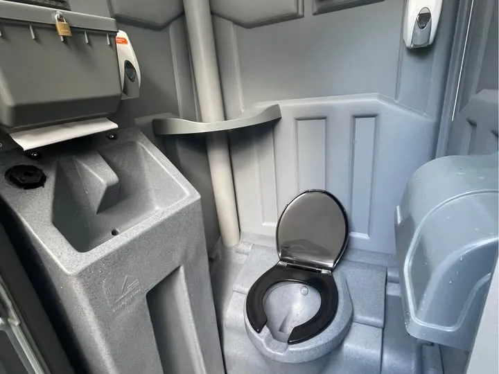 Interior of a deluxe portable restroom with a handwash basin and mirror