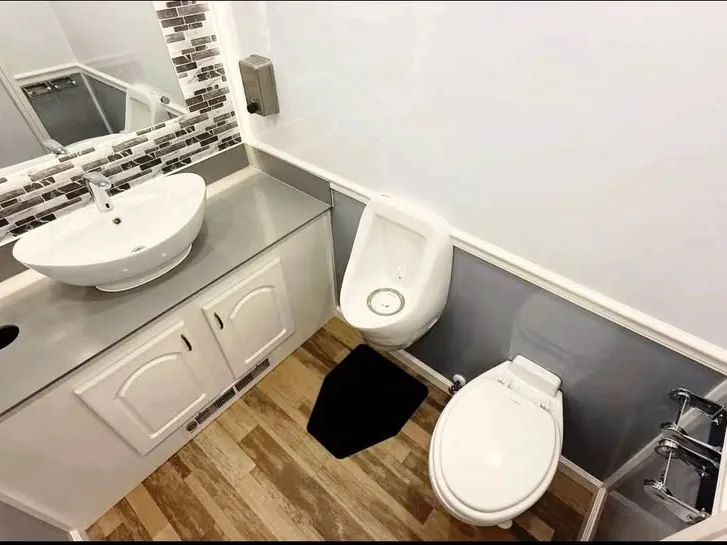 Restroom trailer interior with a vessel basin, mirror and wood-effect floor