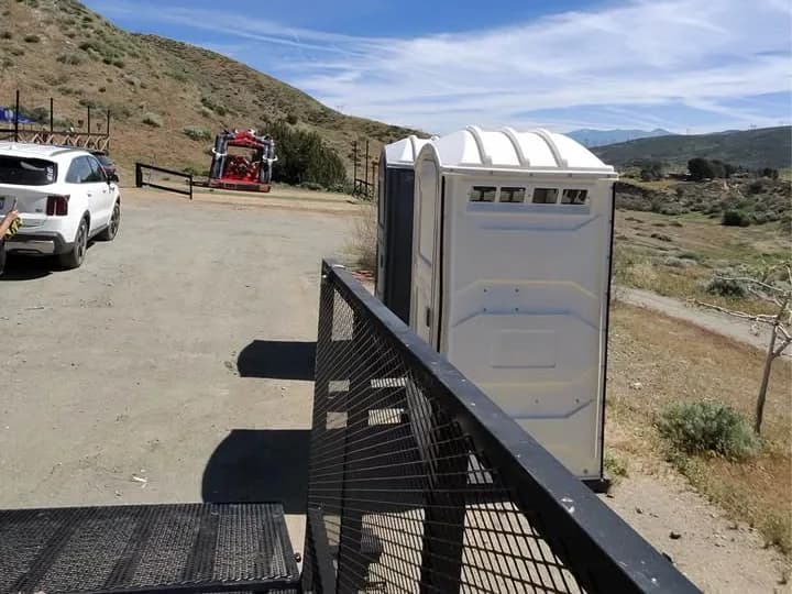Portable restroom being delivered on a flatbed trailer at a work site